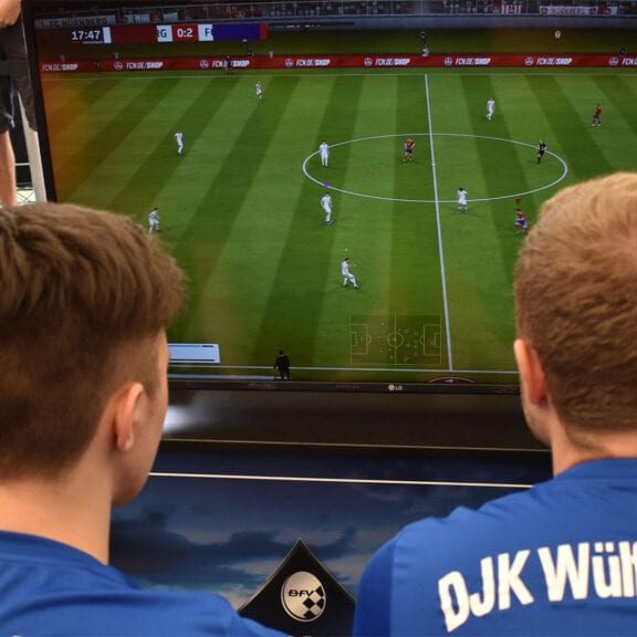 Zwei Personen spielen Fifa an der Playstation